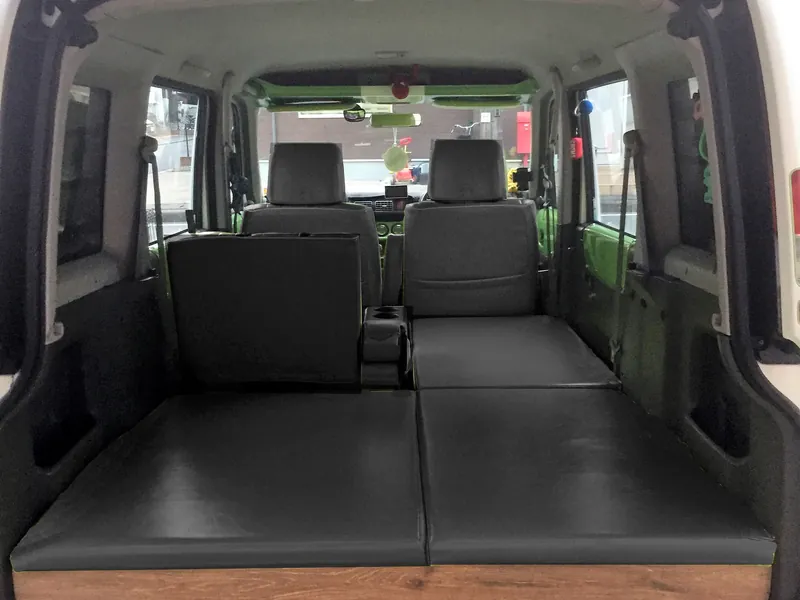 ベッドを展開した軽キャンピングカーの車内