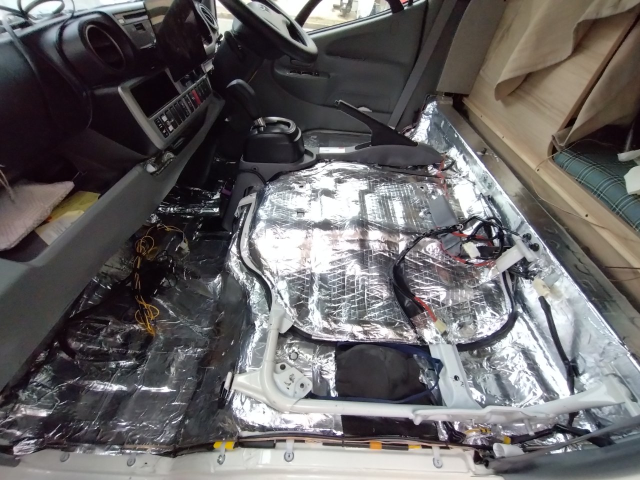 座席を外したカムロードの運転席まわり。フロアとエンジンカバーに制振材・遮熱材を敷き詰めた施工中の車内