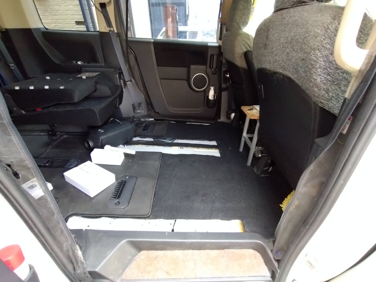 シートを取り外して施工中のミニバン車内。フロアに取付前のFFヒーター本体と部品箱が置かれている