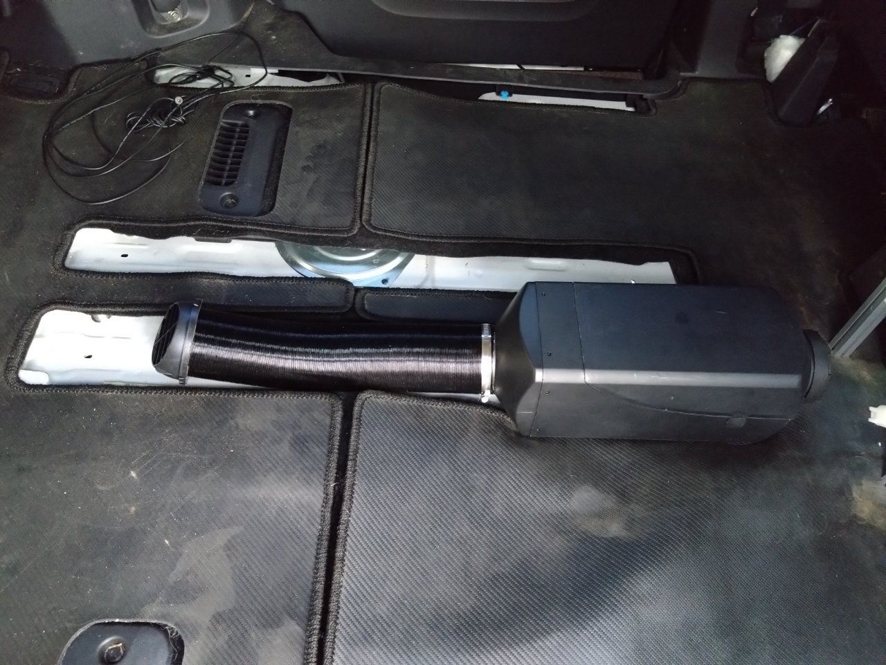 フロアマットをめくった車内に設置したFFヒーター本体と、保温材を巻いた温風ダクト